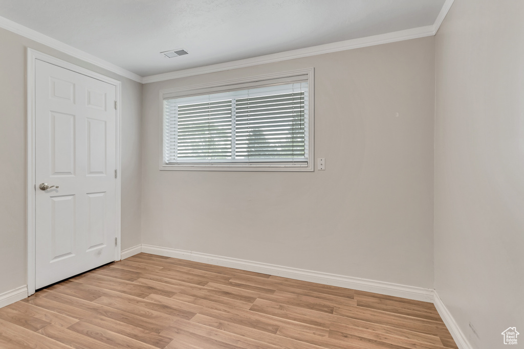 Empty room with light hardwood / wood-style floors and crown molding