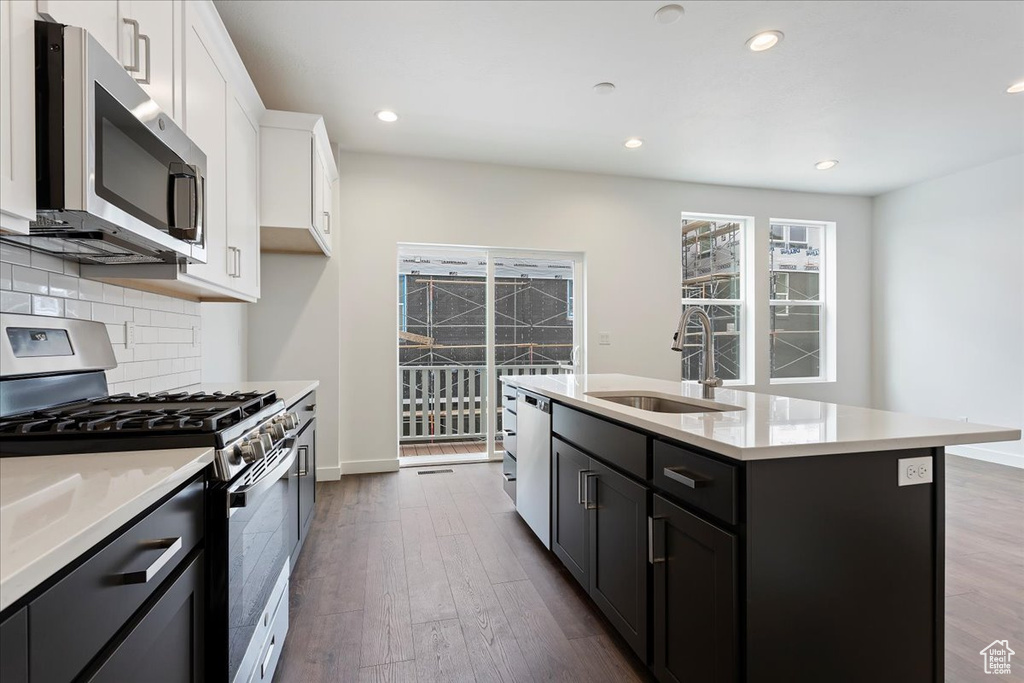 Kitchen featuring hardwood / wood-style floors, sink, appliances with stainless steel finishes, and backsplash