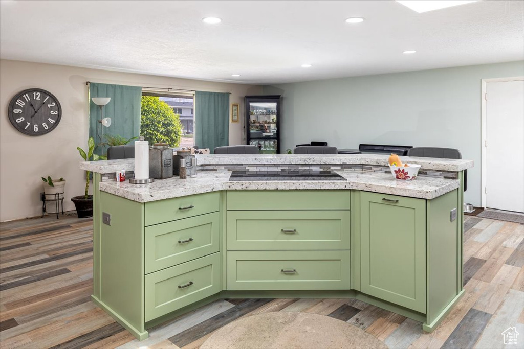 Kitchen featuring a kitchen island, hardwood / wood-style floors, green cabinets, and black electric cooktop