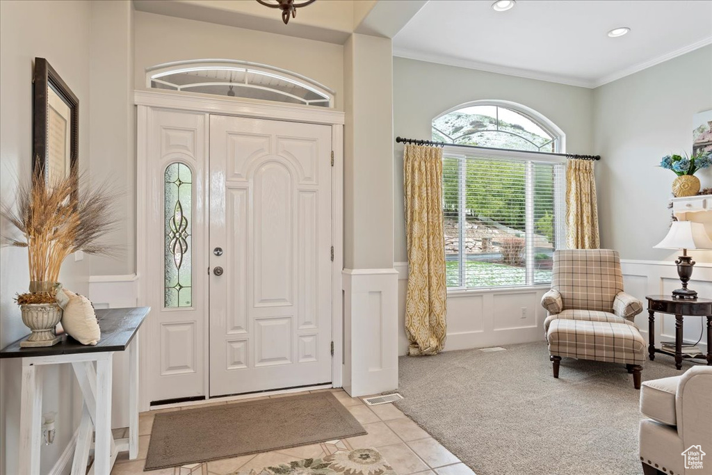 Carpeted entrance foyer featuring plenty of natural light and crown molding