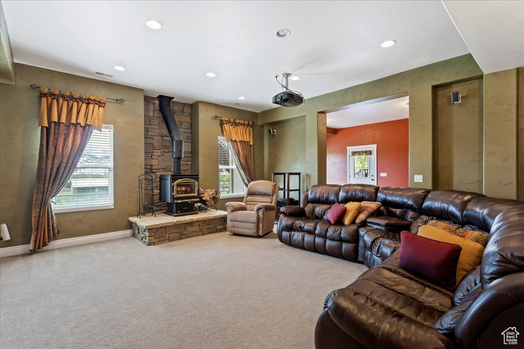Carpeted living room featuring a wood stove and a wealth of natural light
