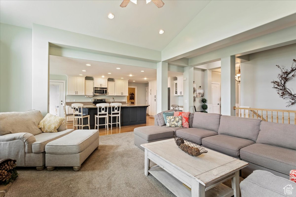 Living room with high vaulted ceiling, sink, ceiling fan, and light colored carpet