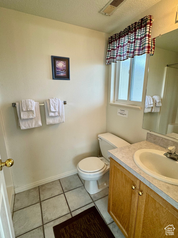 Bathroom featuring a textured ceiling, vanity, tile floors, and toilet