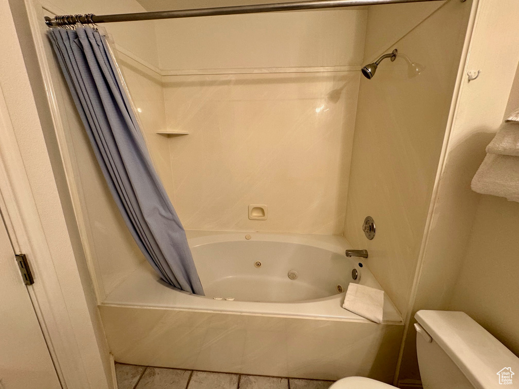 Bathroom with shower / bath combo, tile floors, and toilet