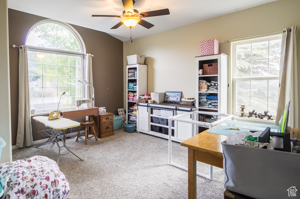 Carpeted home office with plenty of natural light and ceiling fan