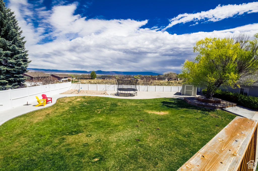View of yard featuring a mountain view, a fire pit, a trampoline, and a patio area