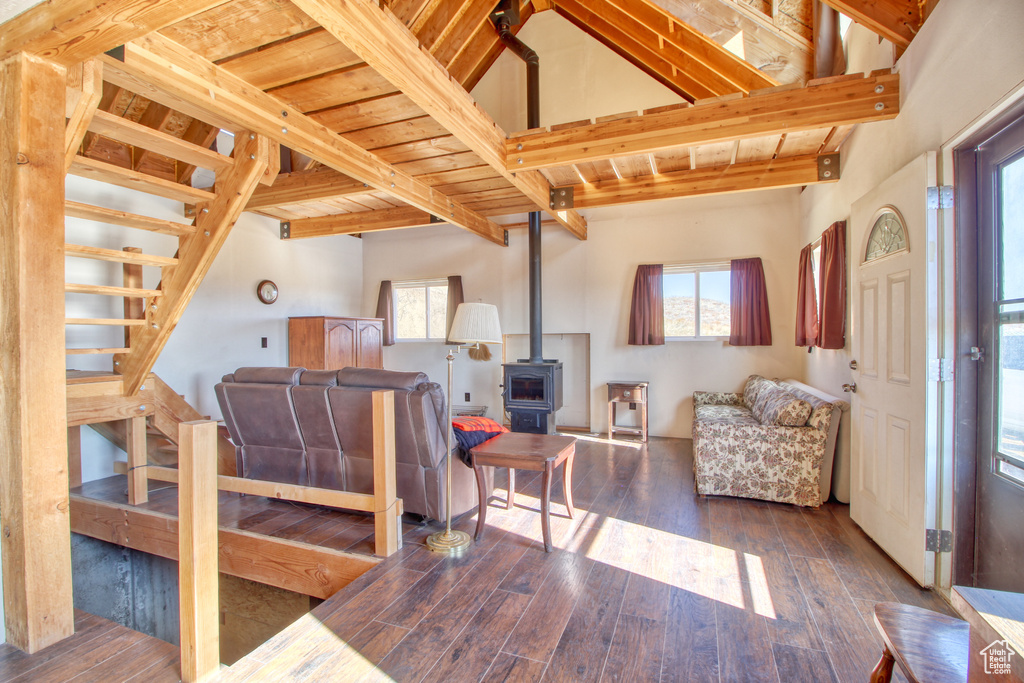 Living room with a wood stove, beam ceiling, a high ceiling, and hardwood / wood-style floors