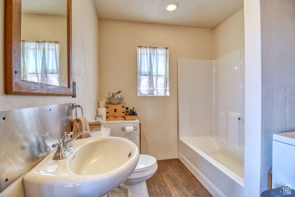 Full bathroom with shower / bathing tub combination, hardwood / wood-style floors, sink, toilet, and a textured ceiling