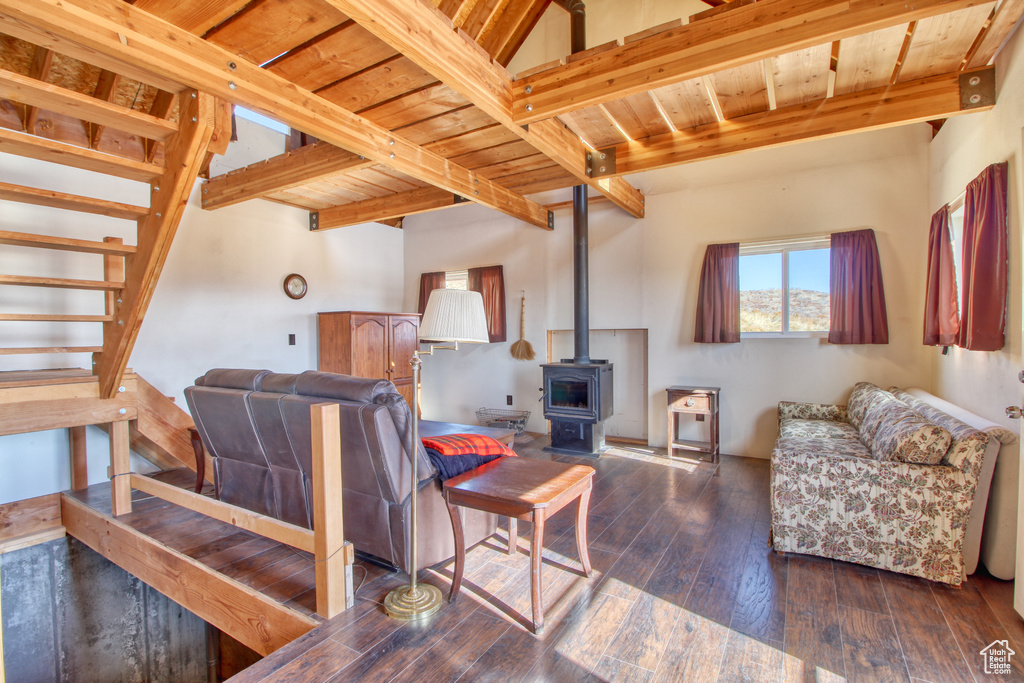 Living room with beamed ceiling, wooden ceiling, a wood stove, and hardwood / wood-style flooring