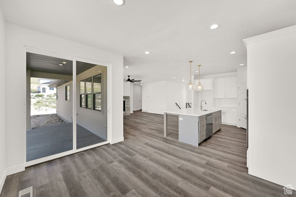 Kitchen featuring ceiling fan, hanging light fixtures, a kitchen island with sink, hardwood / wood-style floors, and sink