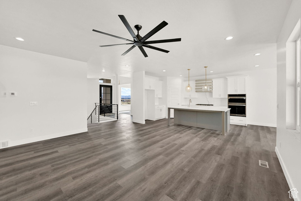 Unfurnished living room with ceiling fan, sink, and dark hardwood / wood-style flooring