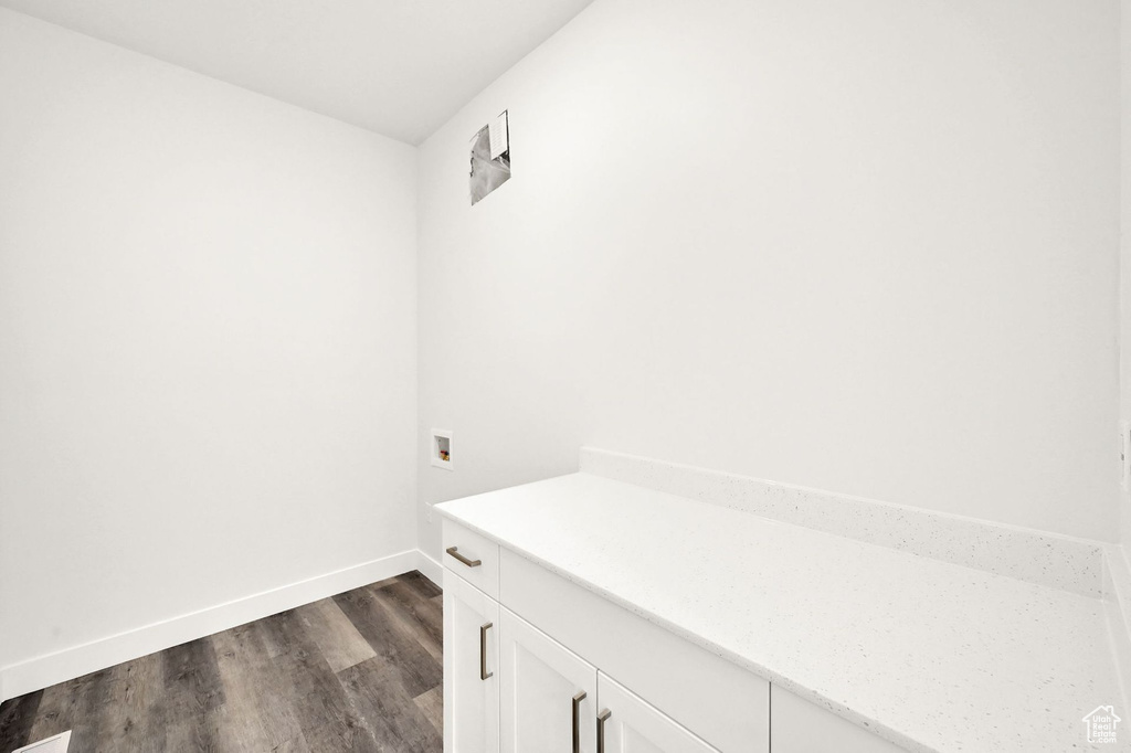 Washroom featuring dark wood-type flooring, washer hookup, and cabinets