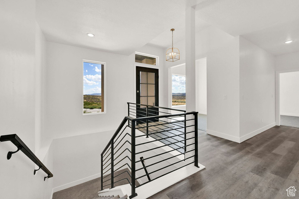 Stairs featuring hardwood / wood-style flooring, a notable chandelier, and plenty of natural light