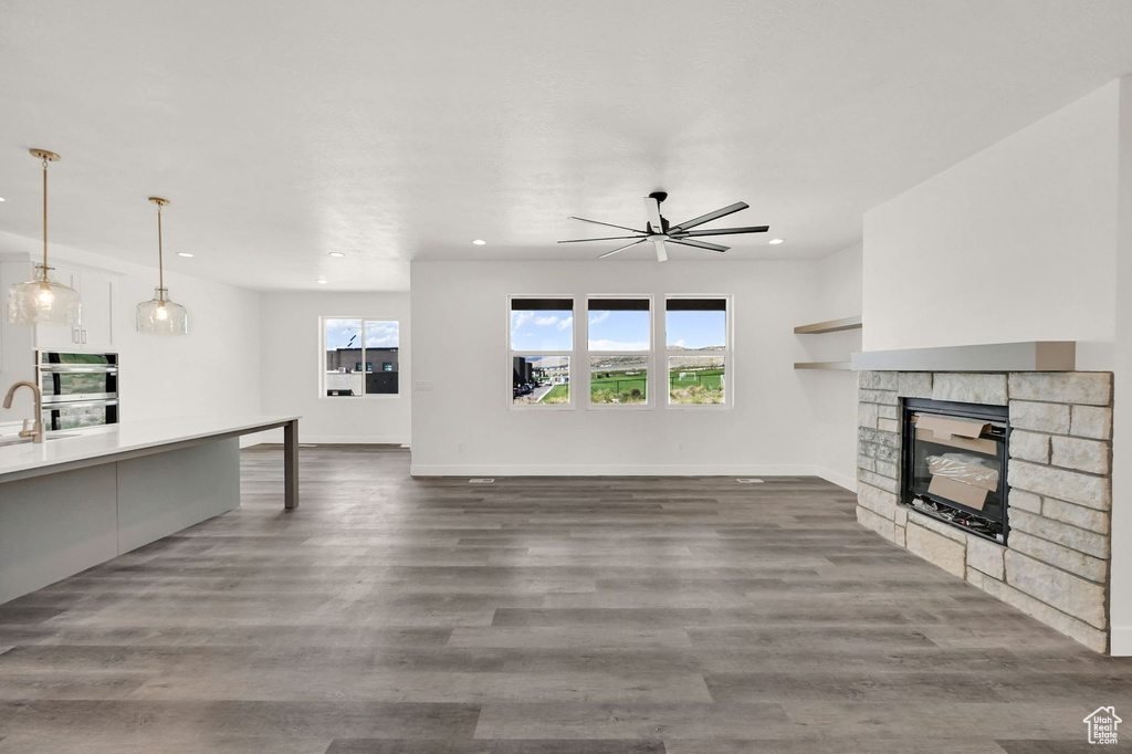 Living room featuring a stone fireplace, ceiling fan, and dark hardwood / wood-style flooring