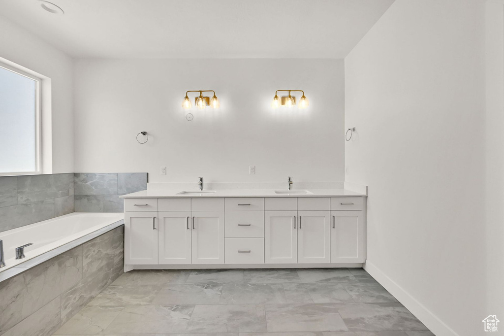 Bathroom featuring tiled bath, vanity, and tile patterned floors