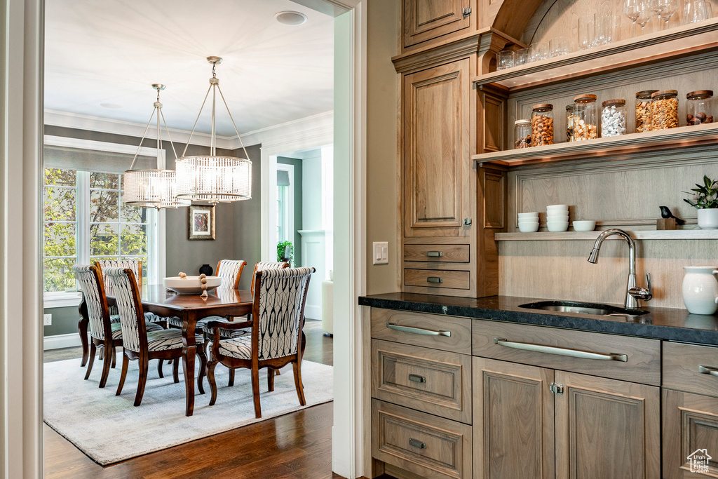 Dining area with a chandelier, ornamental molding, dark wood-type flooring, and sink