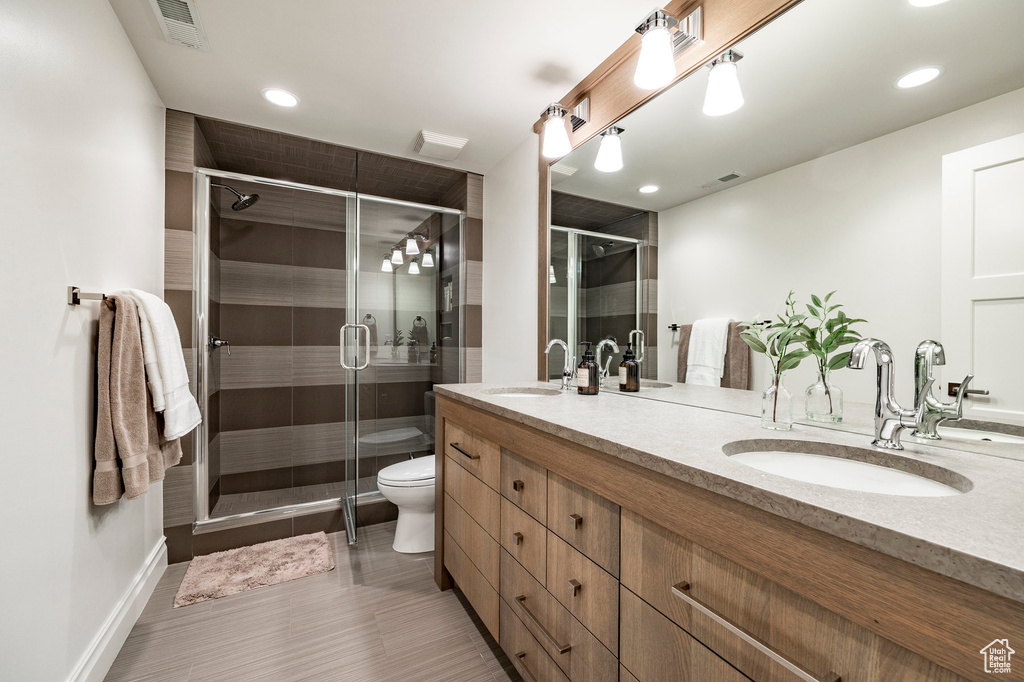 Bathroom featuring walk in shower, tile flooring, toilet, and double sink vanity