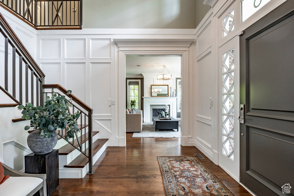 Foyer featuring dark wood-type flooring, crown molding, and a high ceiling