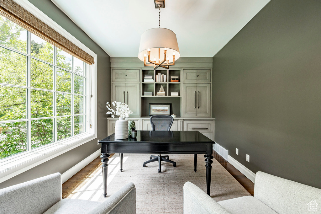 Office with a wealth of natural light, a chandelier, and hardwood / wood-style flooring