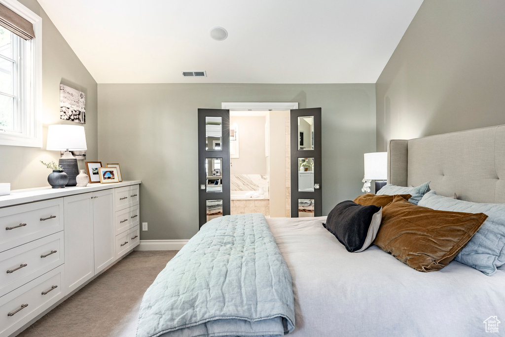 Carpeted bedroom with vaulted ceiling and ensuite bathroom