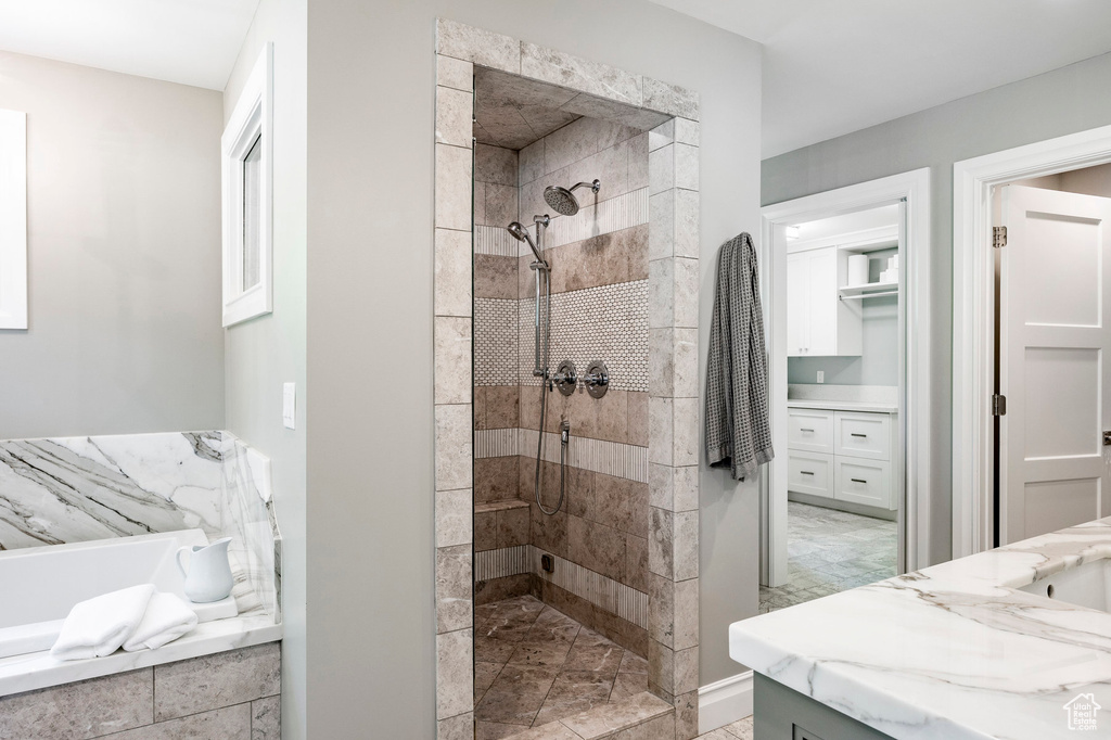 Bathroom featuring tiled shower, vanity, and tile floors