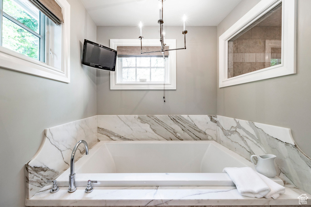 Bathroom featuring a notable chandelier and tiled bath