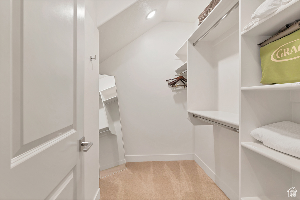 Walk in closet featuring light carpet and vaulted ceiling