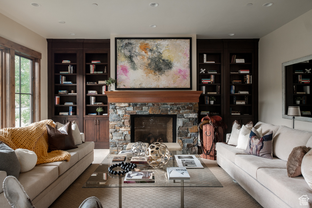 Living room featuring recessed lighting, a stone fireplace, and built in features