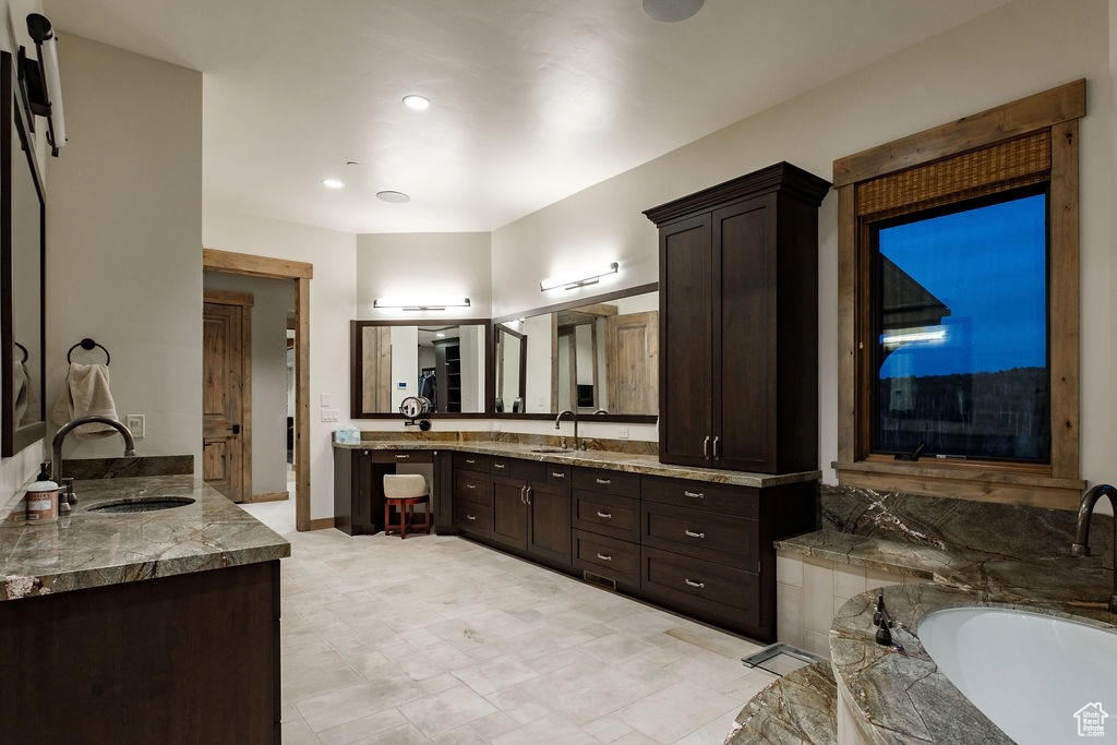 Bathroom featuring double sink, tile floors, large vanity, and a bathing tub