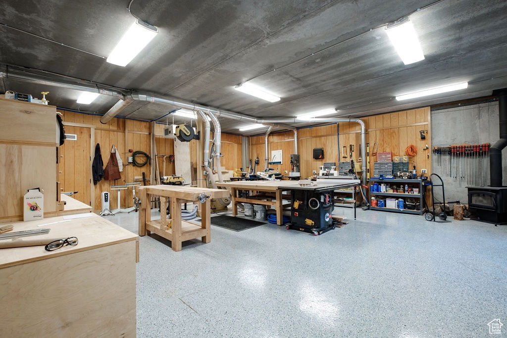 Garage featuring a workshop area, wooden walls, and a wood stove