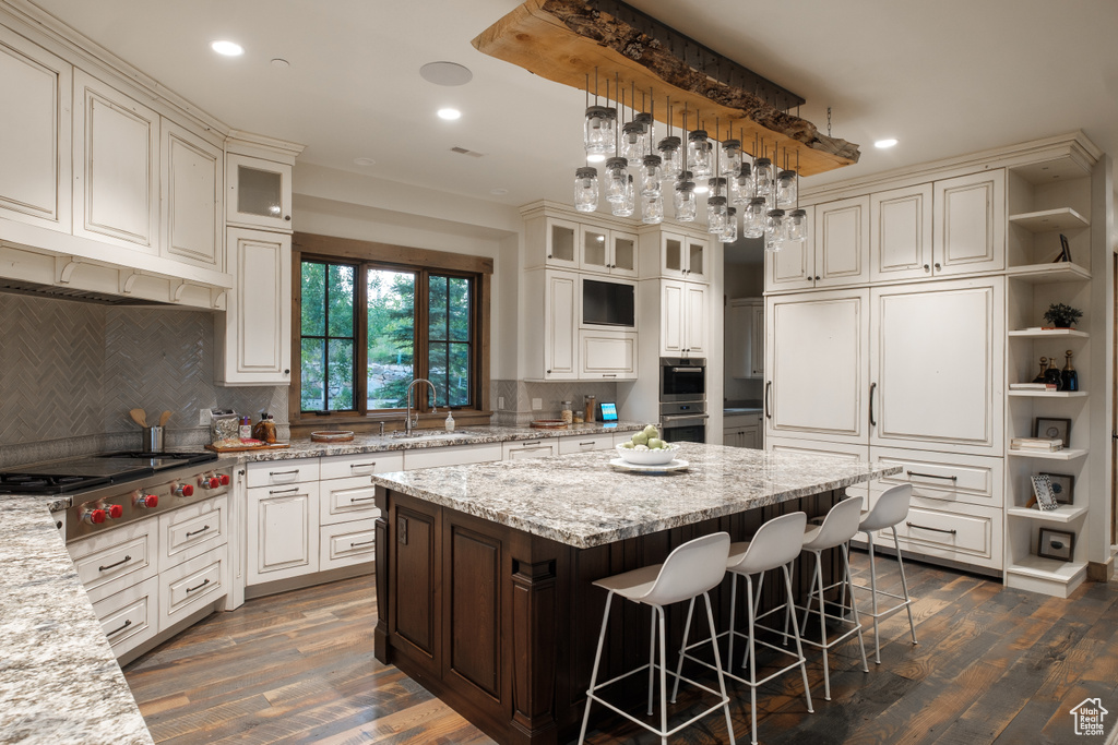 Kitchen featuring a center island, recessed lighting, open shelves, appliances with stainless steel finishes, and a breakfast bar area
