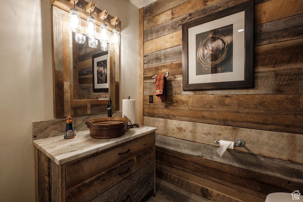 Bathroom with wooden walls, vanity, and toilet