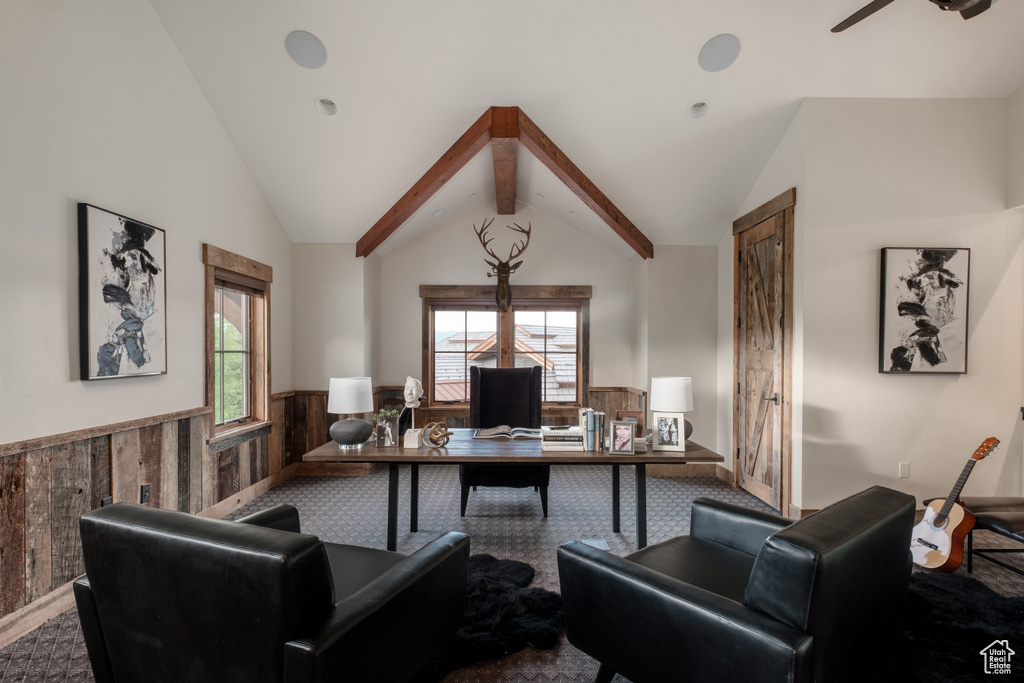 Carpeted home office with wainscoting, ceiling fan, vaulted ceiling, plenty of natural light, and wood walls