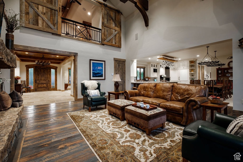 Living room with beam ceiling, a towering ceiling, and wood-type flooring