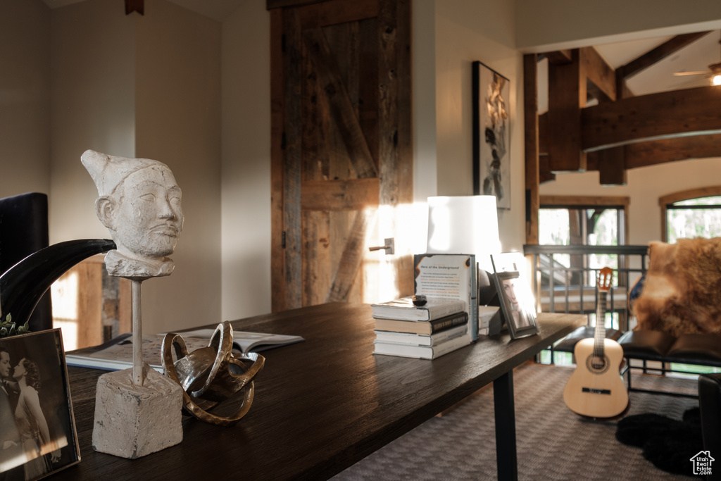 Home office featuring beamed ceiling, ceiling fan, and wood finished floors