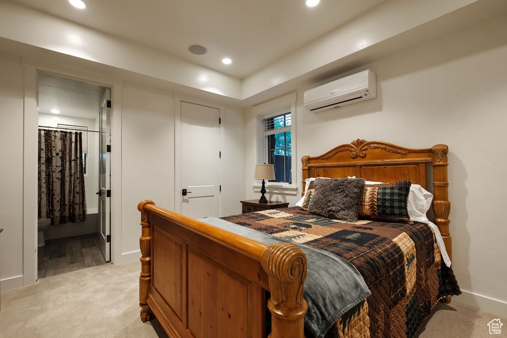 Carpeted bedroom featuring a wall mounted AC and connected bathroom