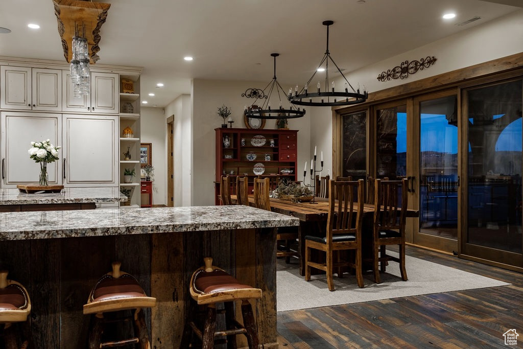 Kitchen featuring light stone counters, cream cabinetry, light hardwood / wood-style flooring, a kitchen breakfast bar, and pendant lighting