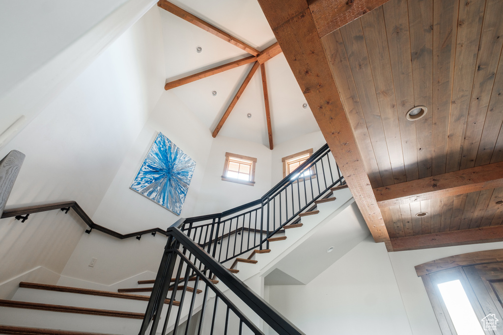 Staircase with high vaulted ceiling and a wooden ceiling with exposed beams