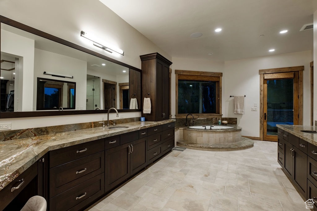 Bathroom featuring tile floors, a relaxing tiled bath, and vanity with extensive cabinet space