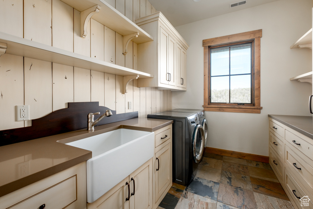 Laundry room with independent washer and dryer, cabinet space, and stone tile flooring