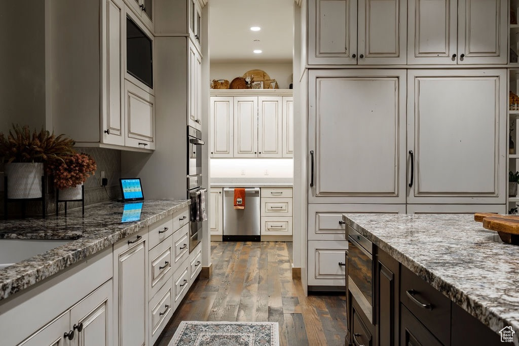 Kitchen featuring light stone counters, appliances with stainless steel finishes, and dark hardwood / wood-style flooring