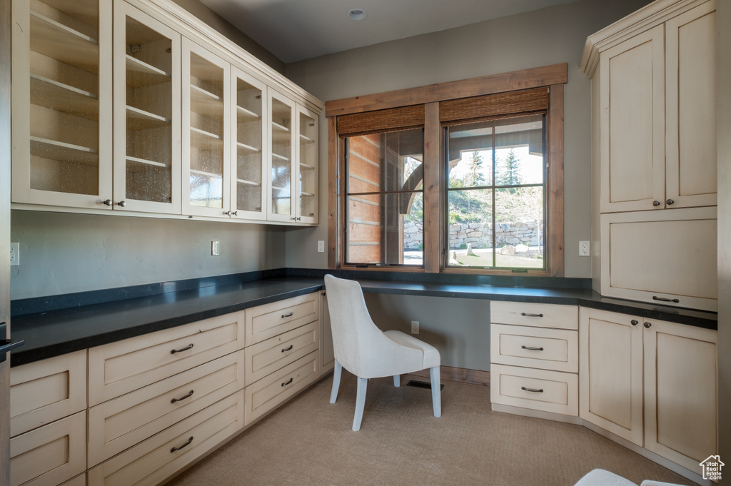 Unfurnished office featuring built in study area and light colored carpet
