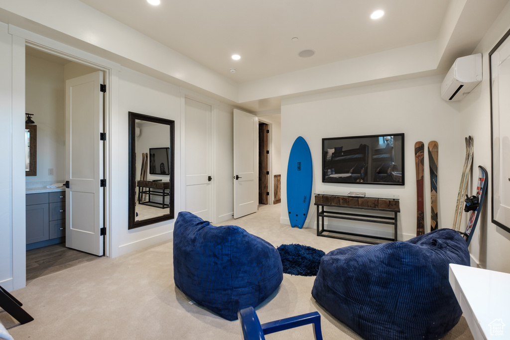 Living area with a wall mounted AC, light colored carpet, and recessed lighting