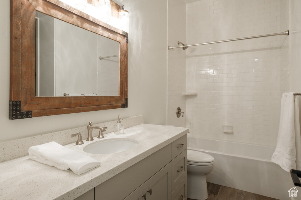 Full bath with vanity, washtub / shower combination, and wood finished floors