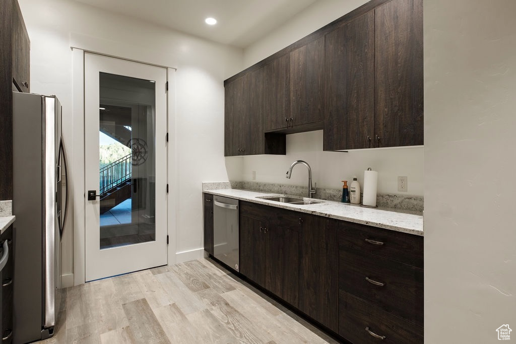 Kitchen with sink, light wood-type flooring, dark brown cabinets, and stainless steel appliances