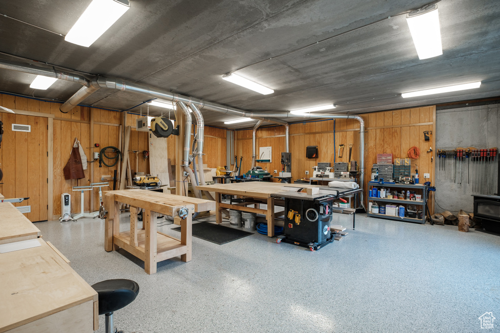 Garage featuring a workshop area, a wood stove, and wooden walls