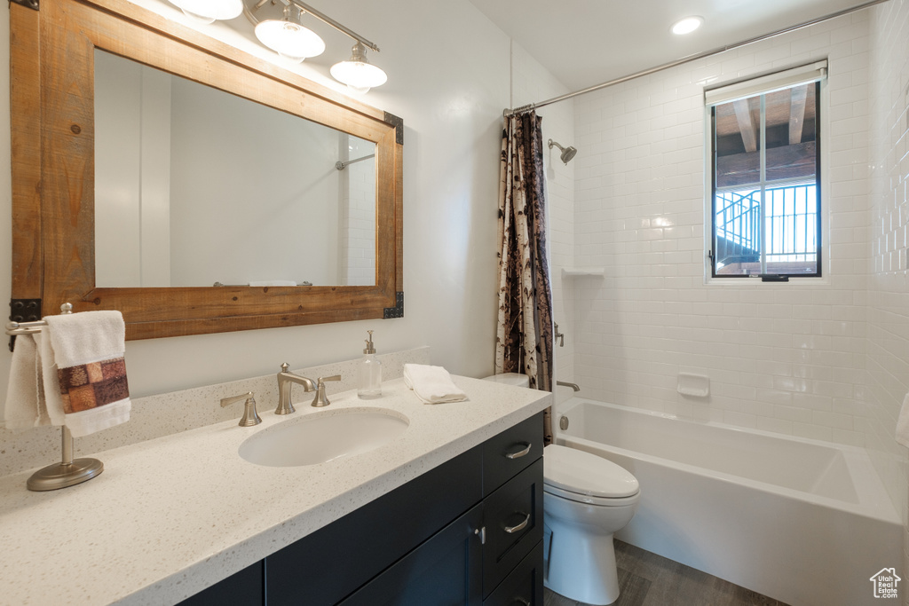 Full bathroom with vanity, shower / bath combination with curtain, and wood finished floors