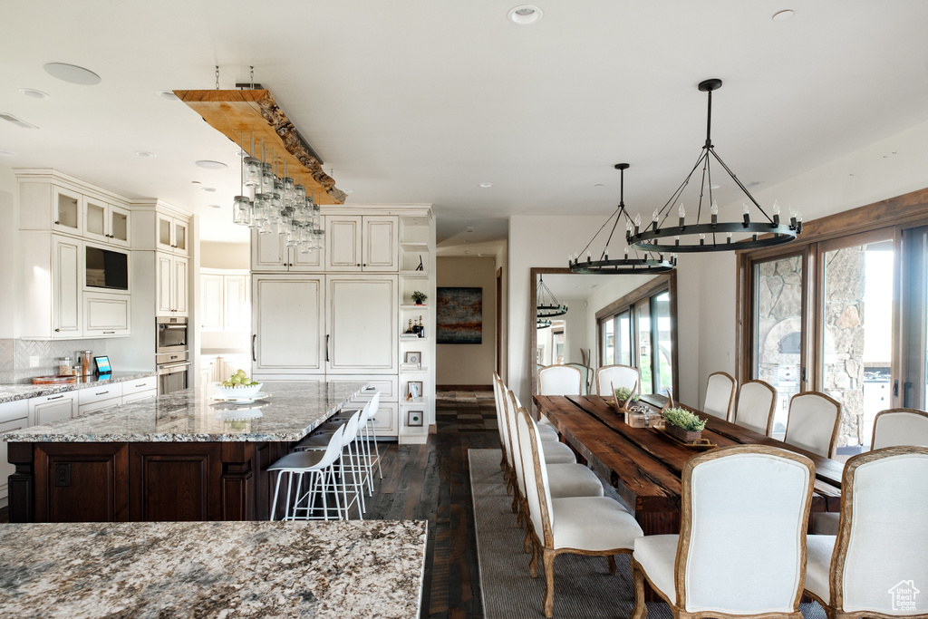 Dining area with a chandelier, dark wood-type flooring, and recessed lighting