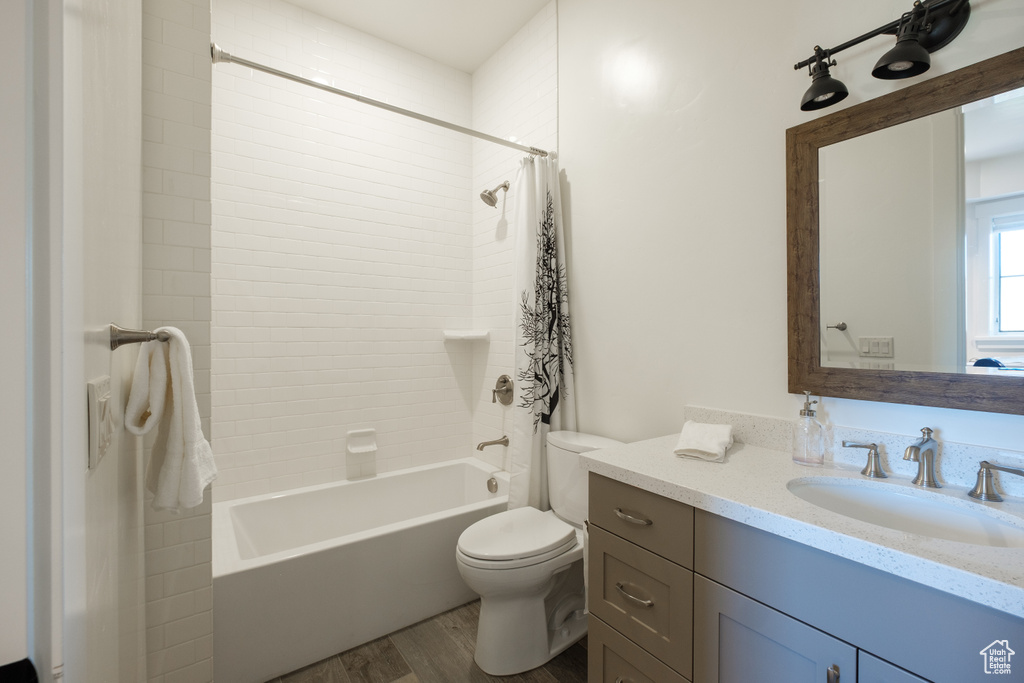 Bathroom with shower / bathtub combination with curtain, vanity, and wood finished floors