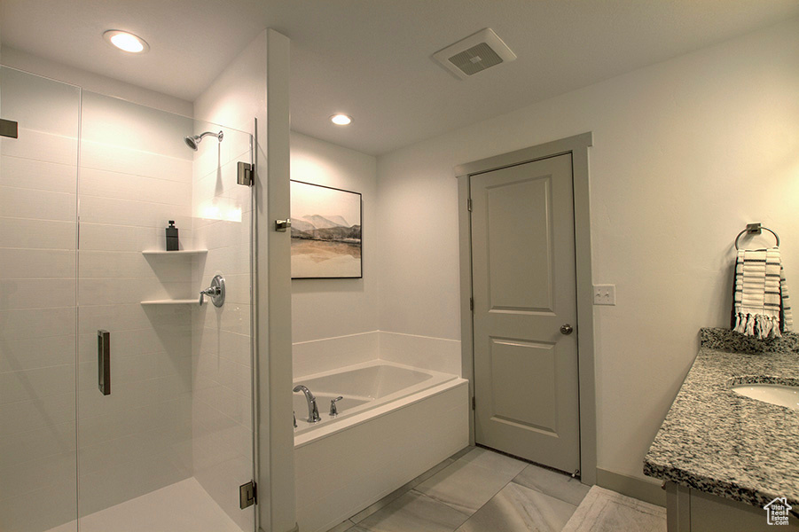 Bathroom featuring plus walk in shower, vanity, and tile flooring